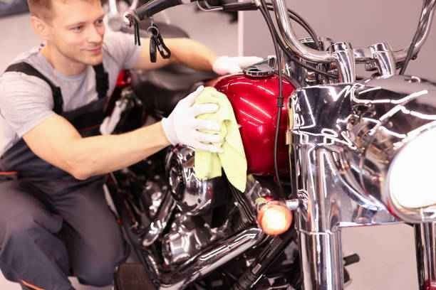 Man polishing a red motorcycle with a cloth in a garage