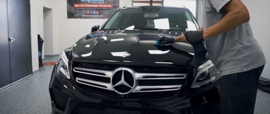 Black Mercedes SUV being washed in a car detailing bay by a worker