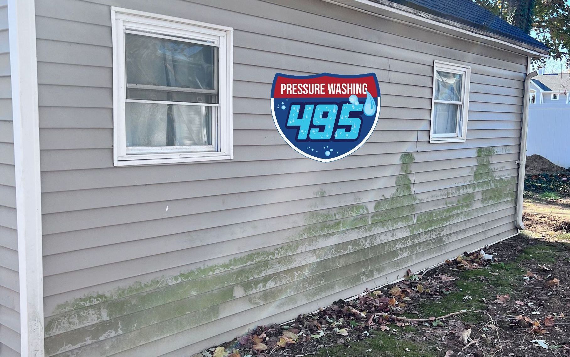 A weathered building with a large Interstate 495 sign and green algae growth on its siding.