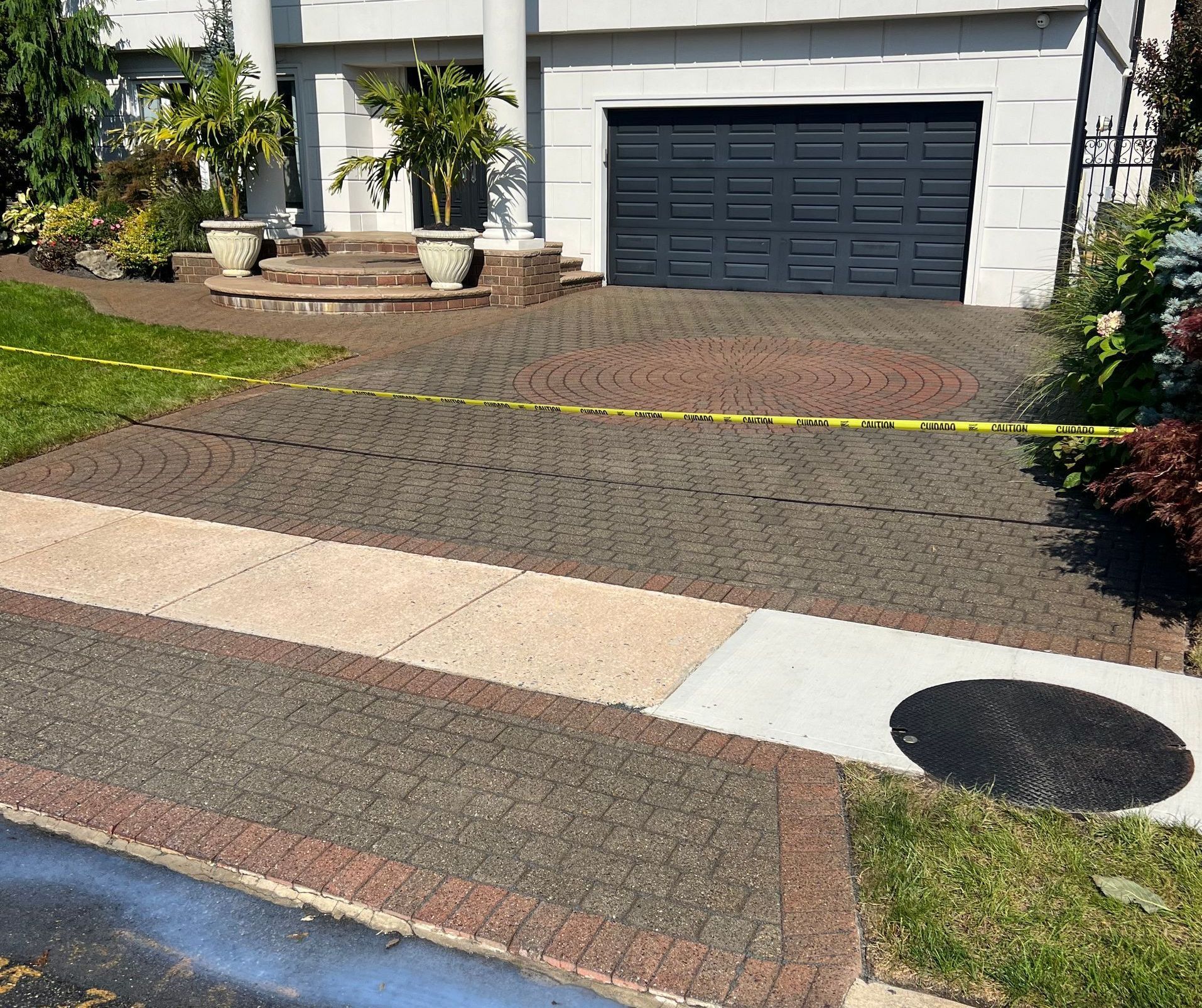 Brick driveway and sidewalk in front of a house, marked with caution tape.