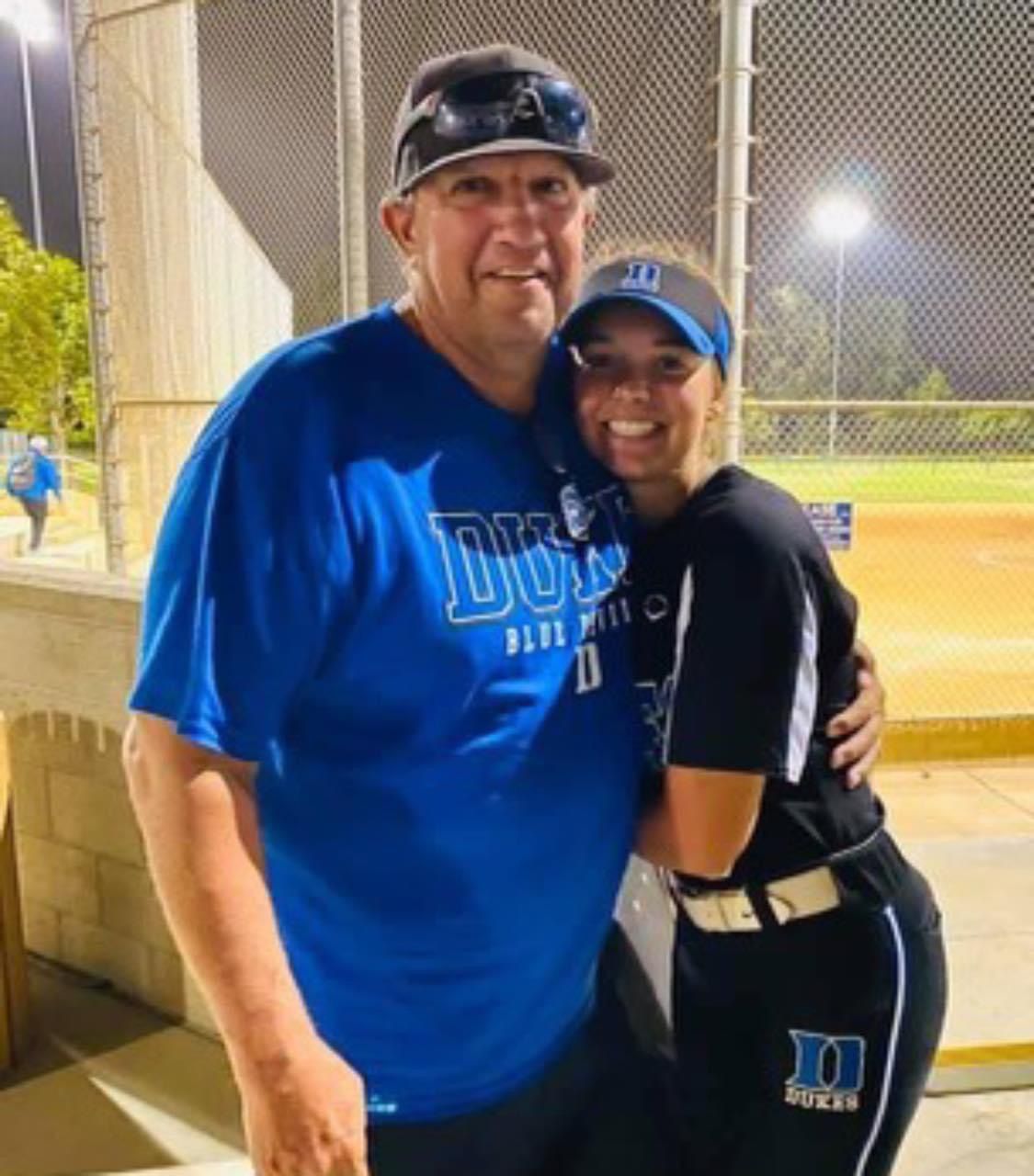 A man wearing a blue shirt that says Duke is hugging a woman — Elkton, MD — Maryland Legends Baseball