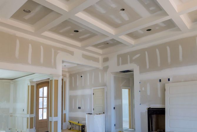 Partially finished room with drywall, coffered ceiling, and doors during renovation