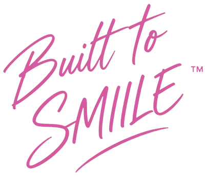 Pink “Built to Smile” script logo on white background with TM symbol