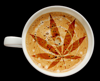 White coffee cup with foamy latte art of a cannabis leaf on a dark background