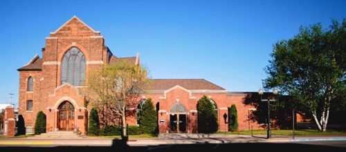 A large brick building with a large window and trees in front of it