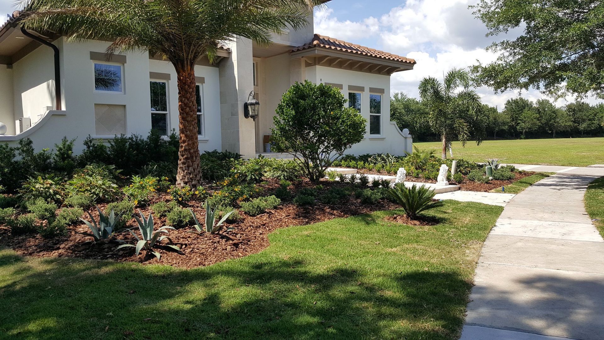 Front yard with landscaped flower beds, sidewalk, and house.