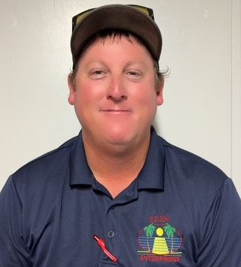 Man wearing a baseball cap and blue shirt, looking at the camera.