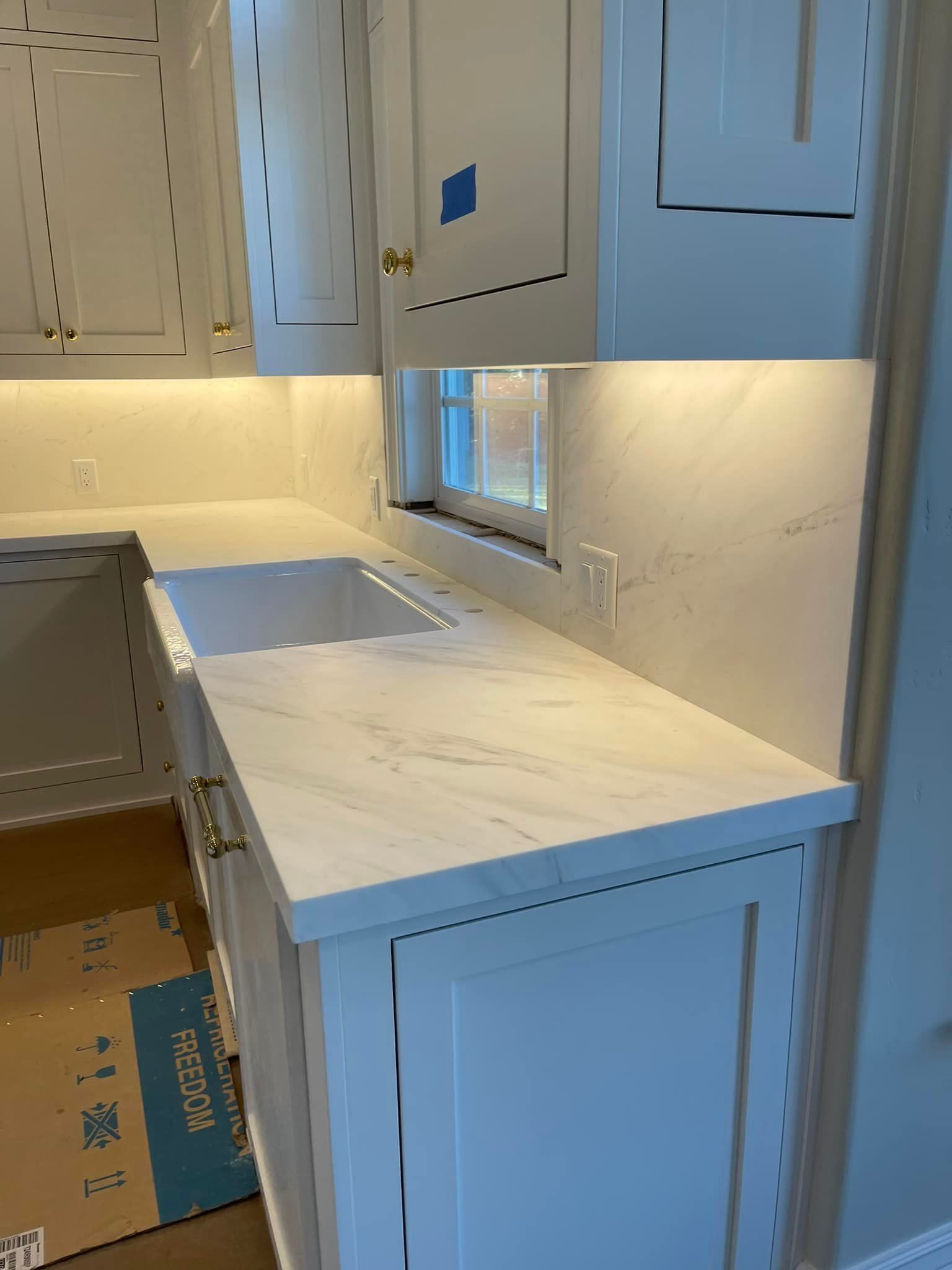 White kitchen with marble countertops, under-cabinet lighting, and cabinets.