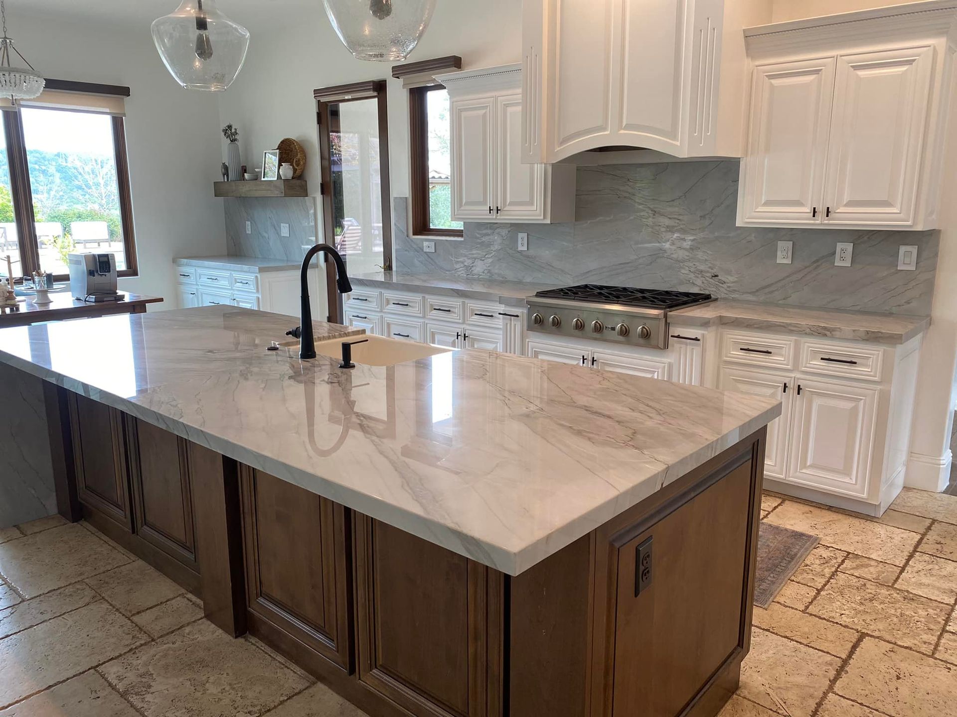 Kitchen with a large island, white cabinets, and a stainless steel range. Brown island cabinets, light countertops.