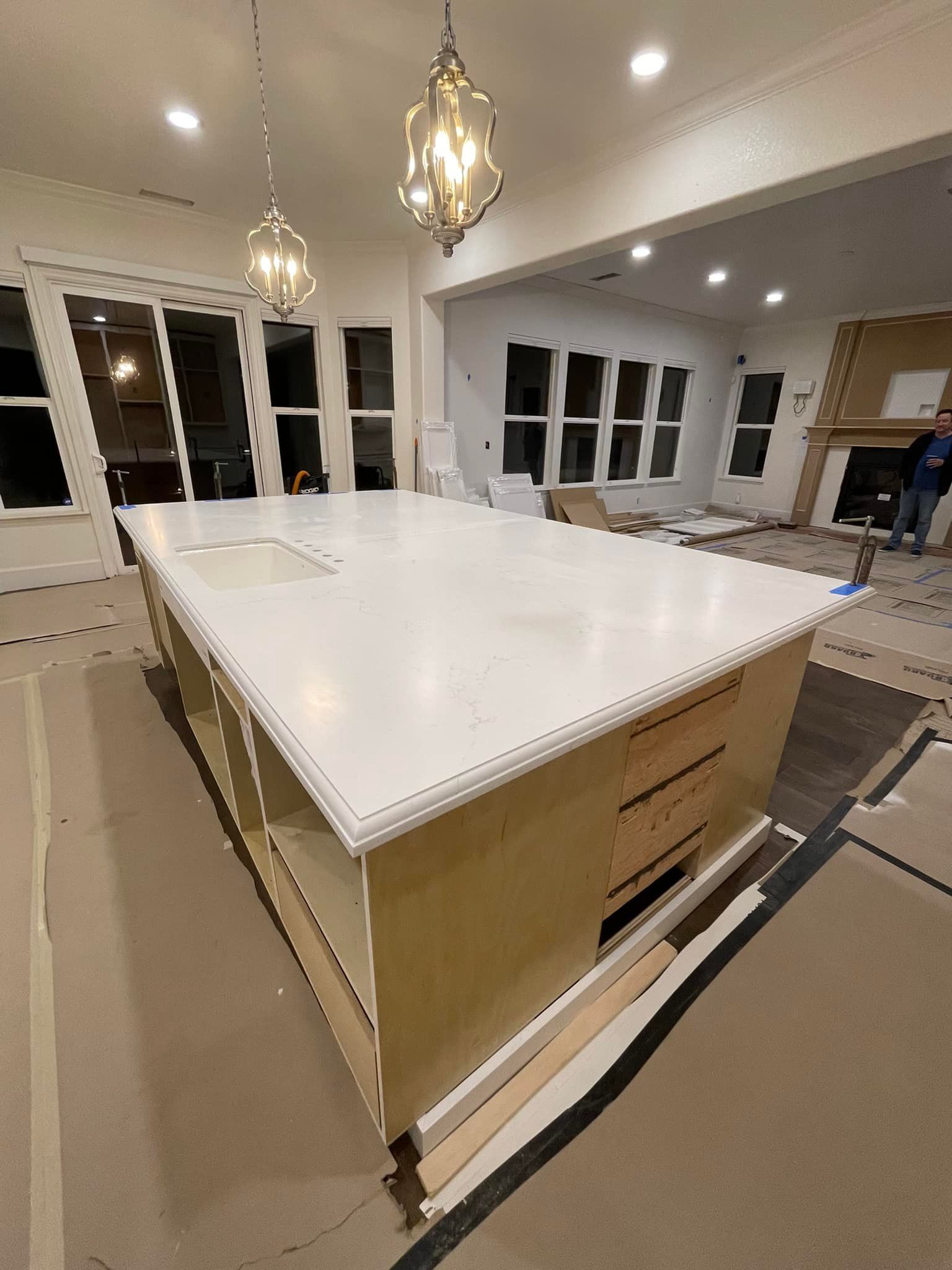 Kitchen island with white countertop, drawers, and open shelving. Two pendant lights hang above.