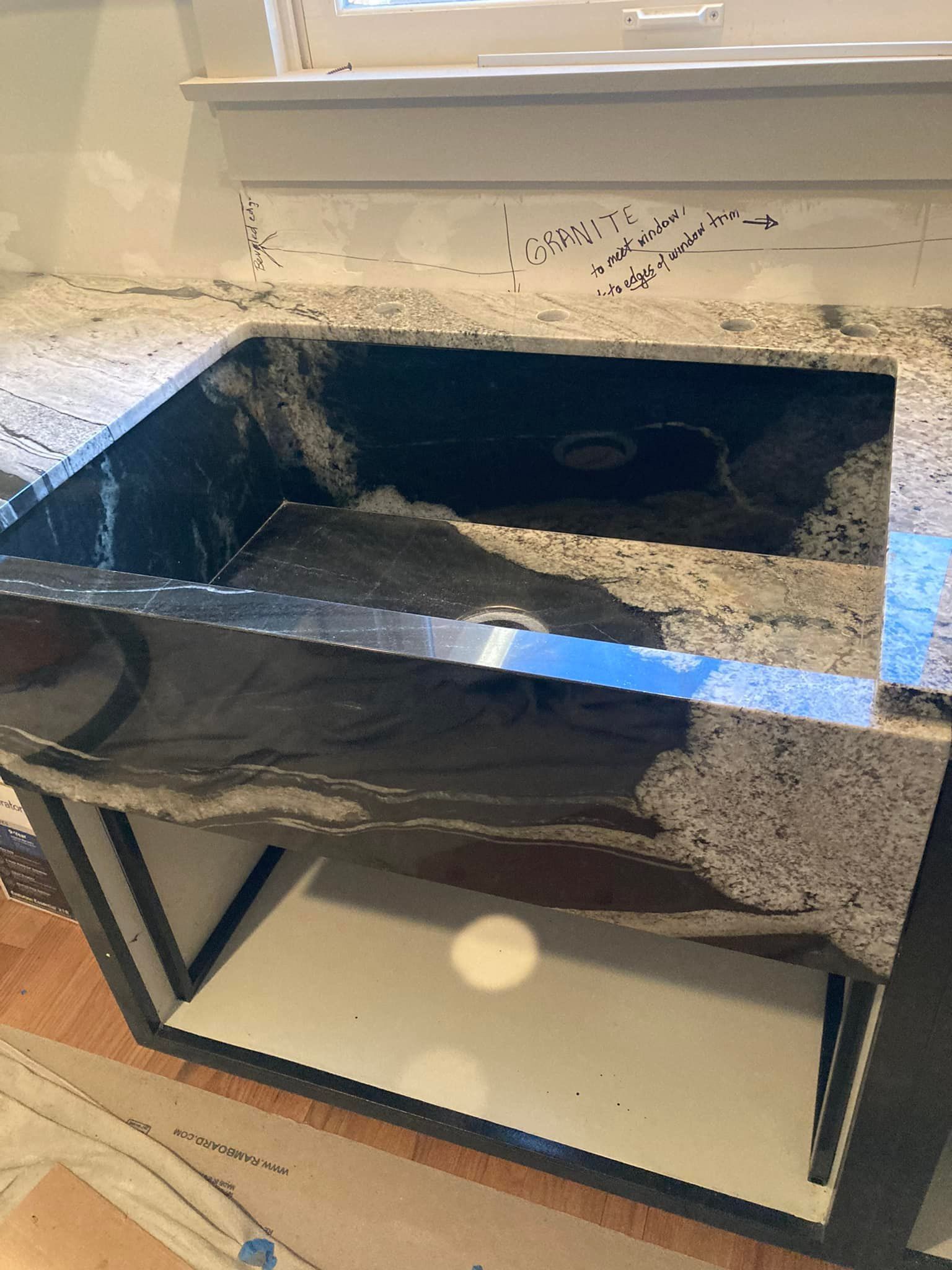 Granite countertop with a built-in black sink, resting on a white cabinet with a dark metal frame.