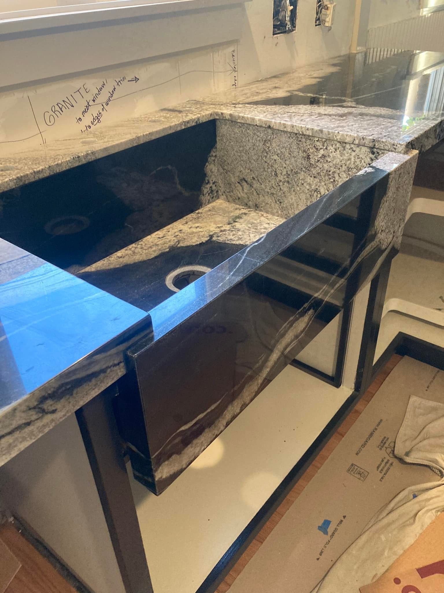 Black granite farmhouse sink installed in a kitchen countertop.