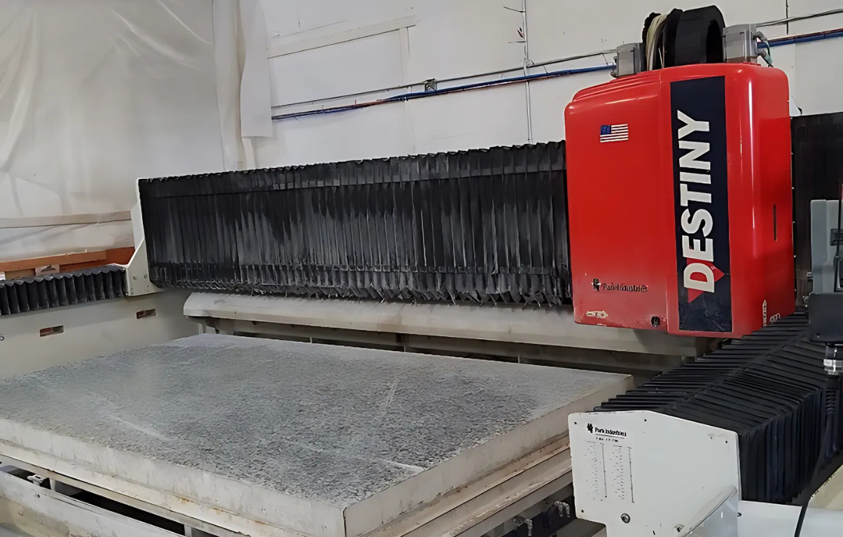 Red Destiny stone cutting machine cutting a large, gray slab in a workshop.
