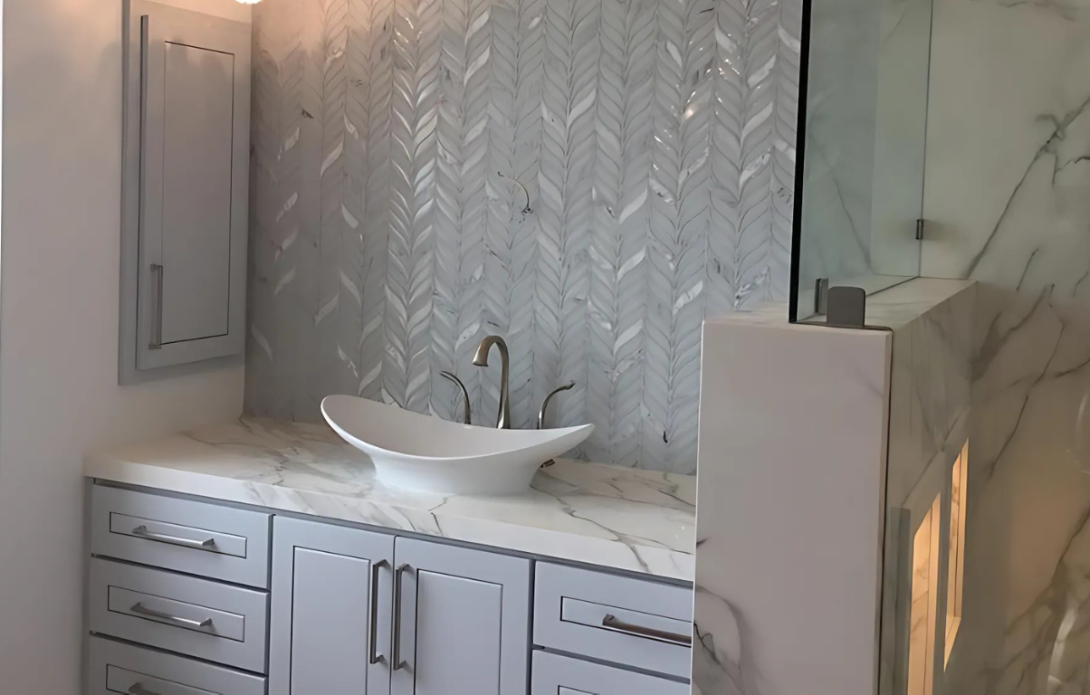 Bathroom with gray cabinets, white sink, and patterned tile backsplash.