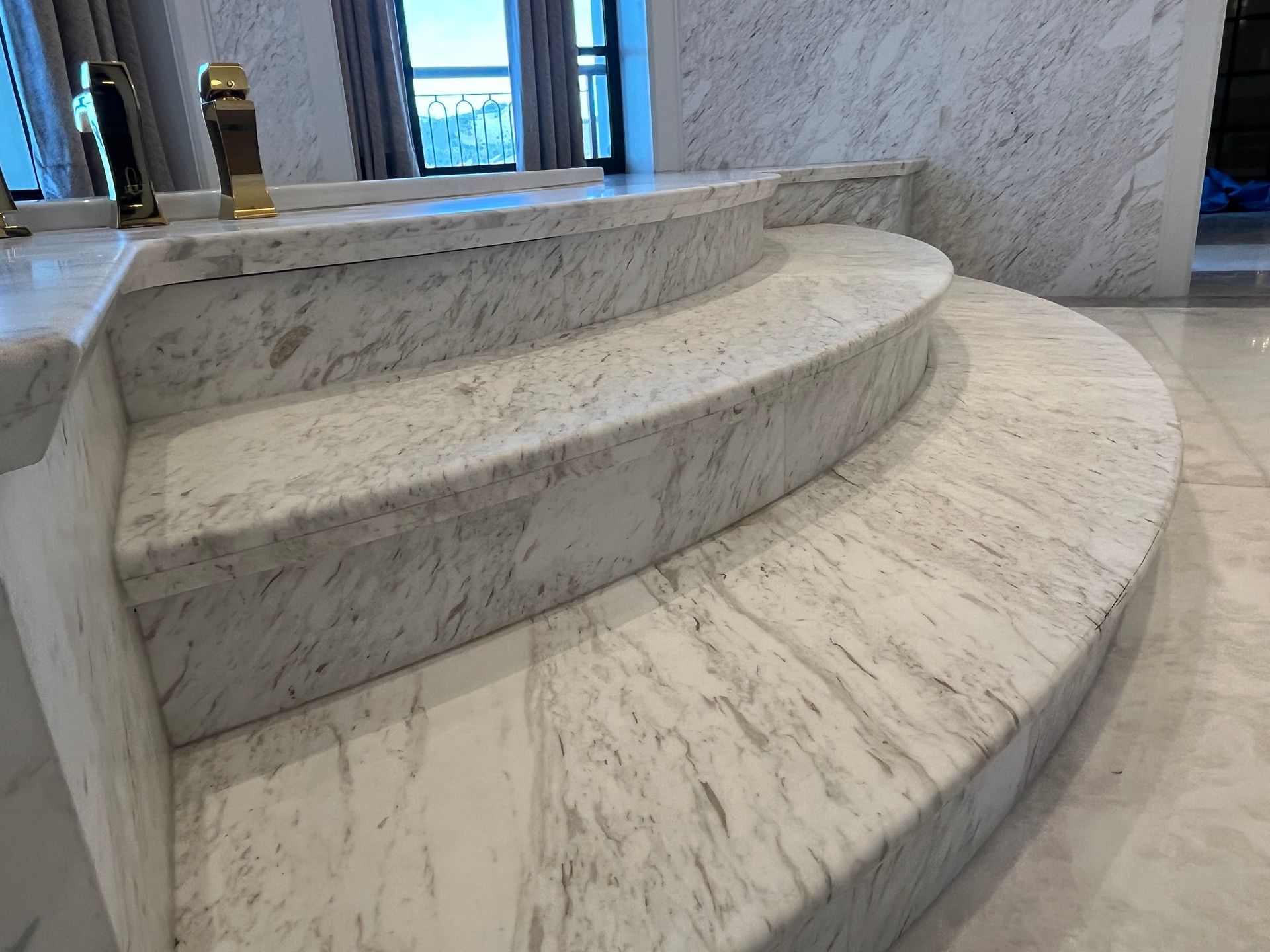 Marble steps leading up to a built-in tub, with a bright, modern interior.