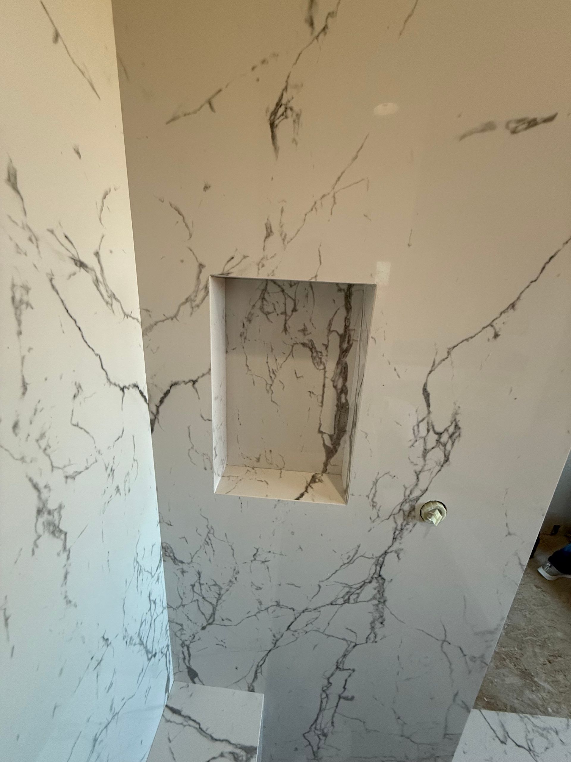 White marble tiled wall with a recessed shelf. Dark gray veining throughout.