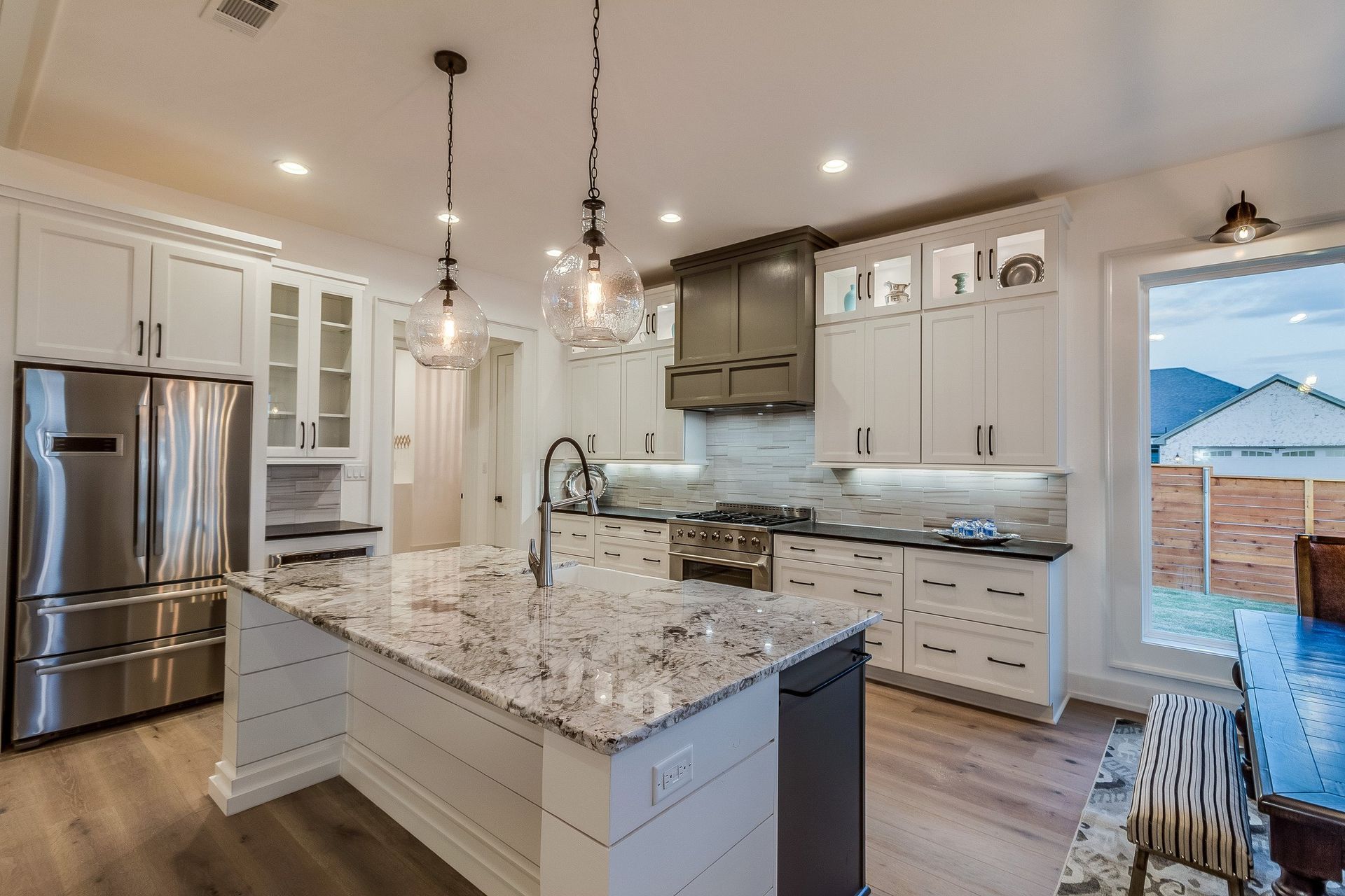 A kitchen with white cabinets , granite counter tops , stainless steel appliances and a large island.