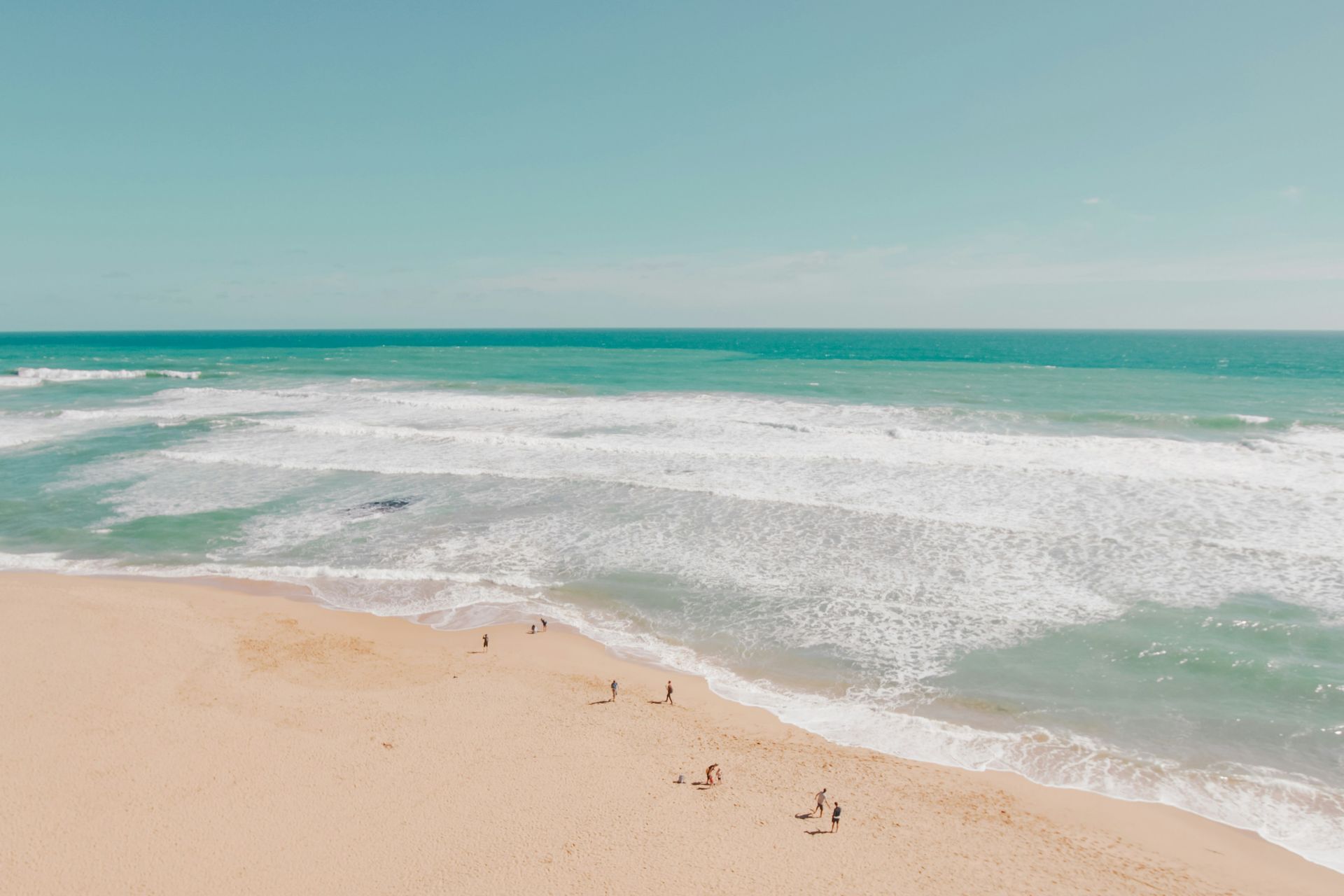 Sandy beach with turquoise waves under a clear blue sky