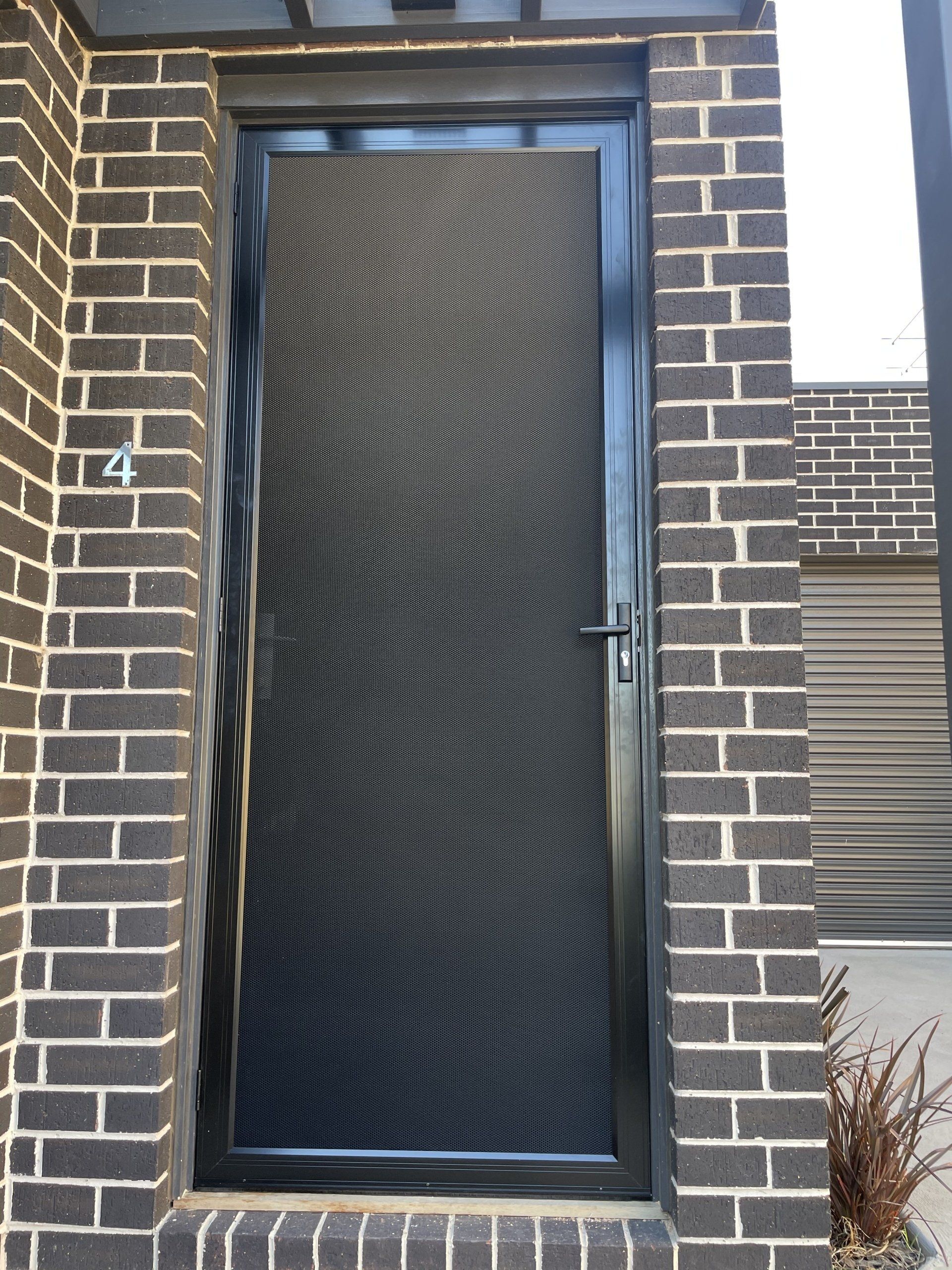 A brick building with a black Security Door and the number 4 on it