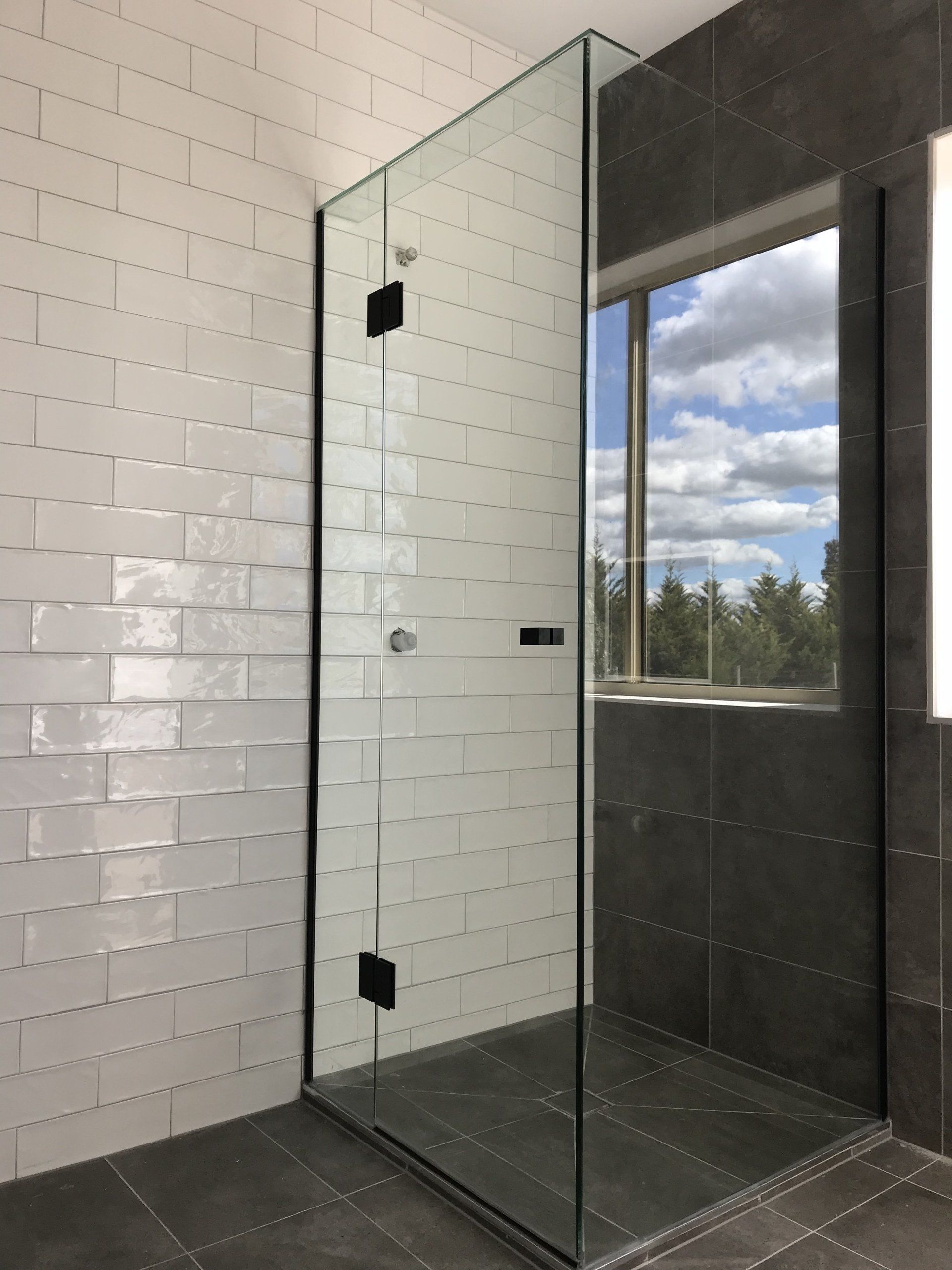 A bathroom with a walk in shower and a window.