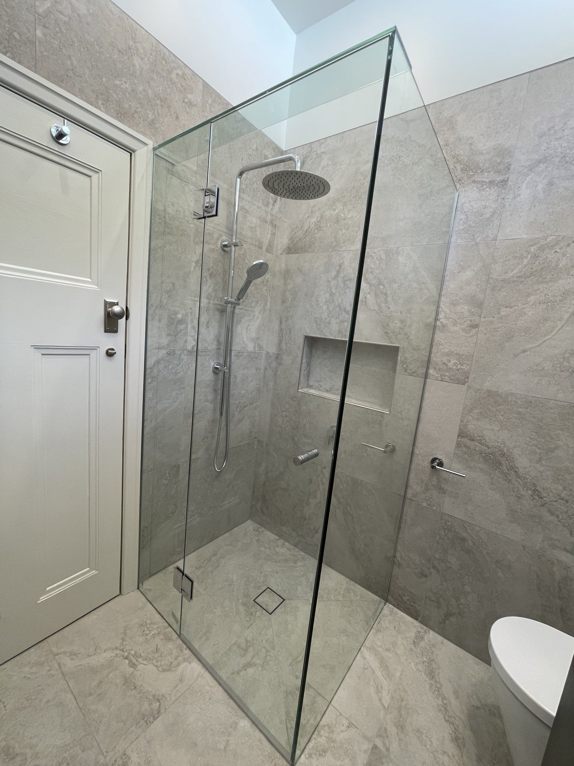 A bathroom with a walk in Frameless Hinged Shower Screen and a toilet