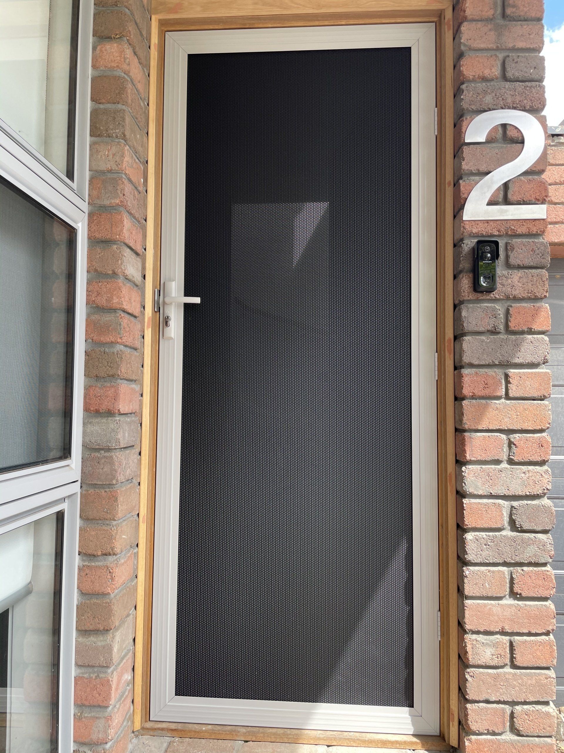 A brick building with a screen Security Door and the number 2 on it.
