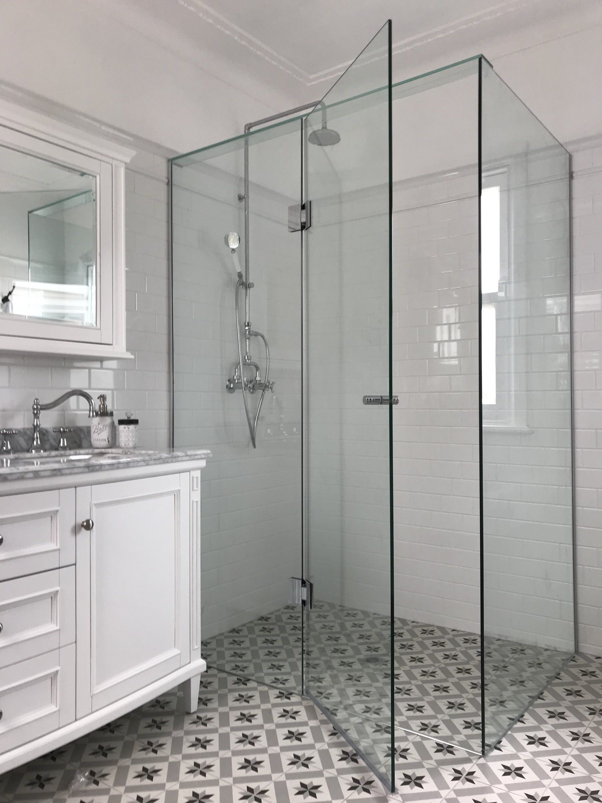 A bathroom with a walk in Frameless Hinged Shower Screen and a sink.