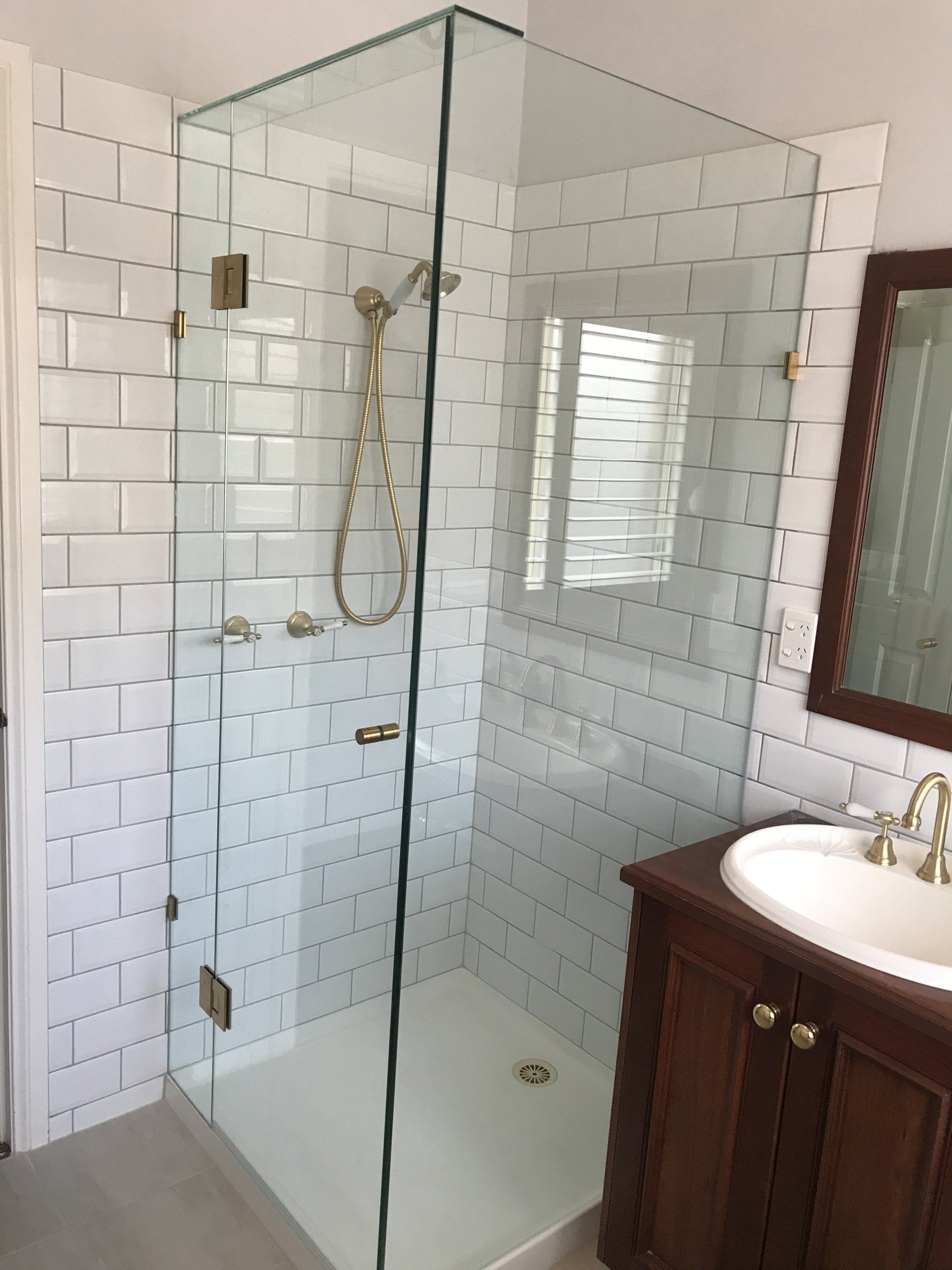 A bathroom with a walk in shower and a sink