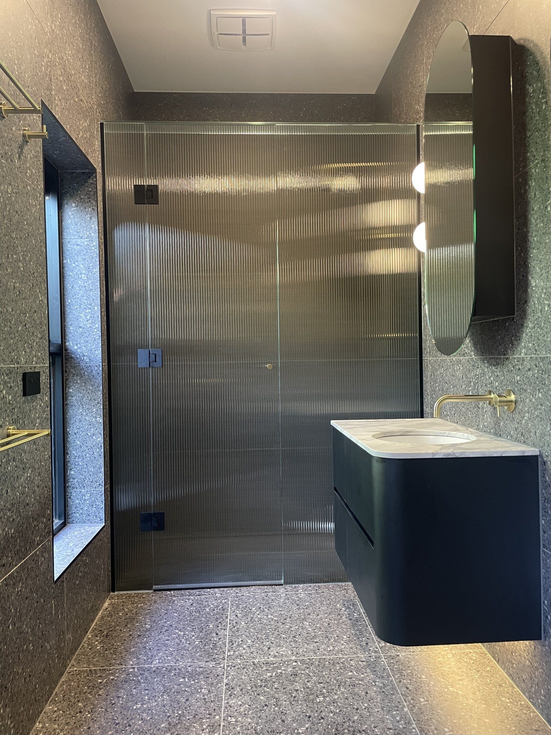 A bathroom with a Frameless Hinged Shower Screen door and a sink.