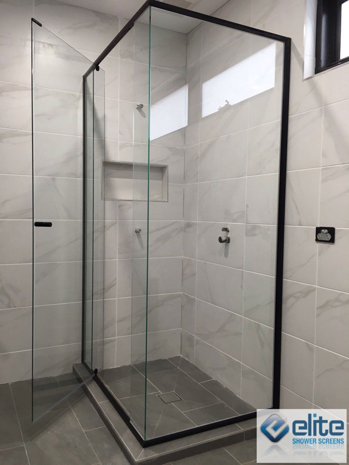 Evolution Semi Frameless shower stall with a black frame and glass doors in a bathroom.