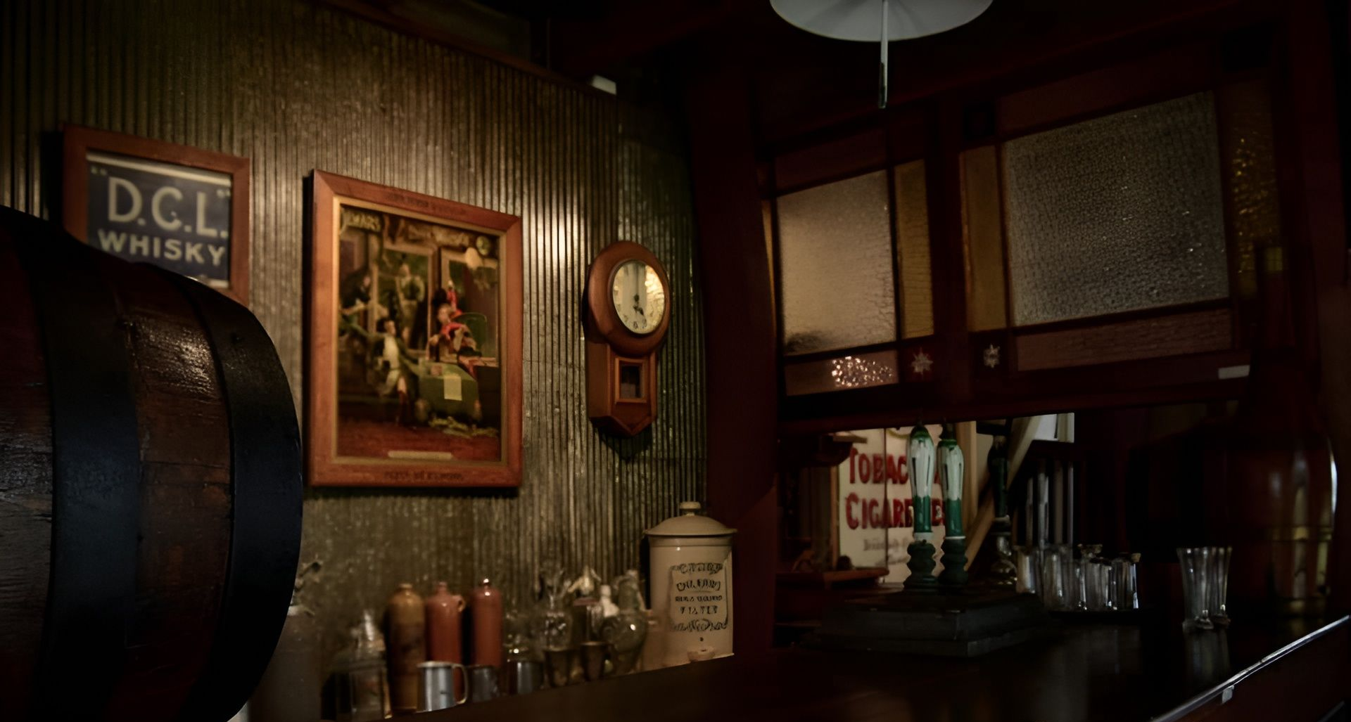 Dim rustic bar interior with whiskey barrel, framed art, clock, and bottles on a wooden counter — Amanda Jade Photography In Gordonvale, QLD