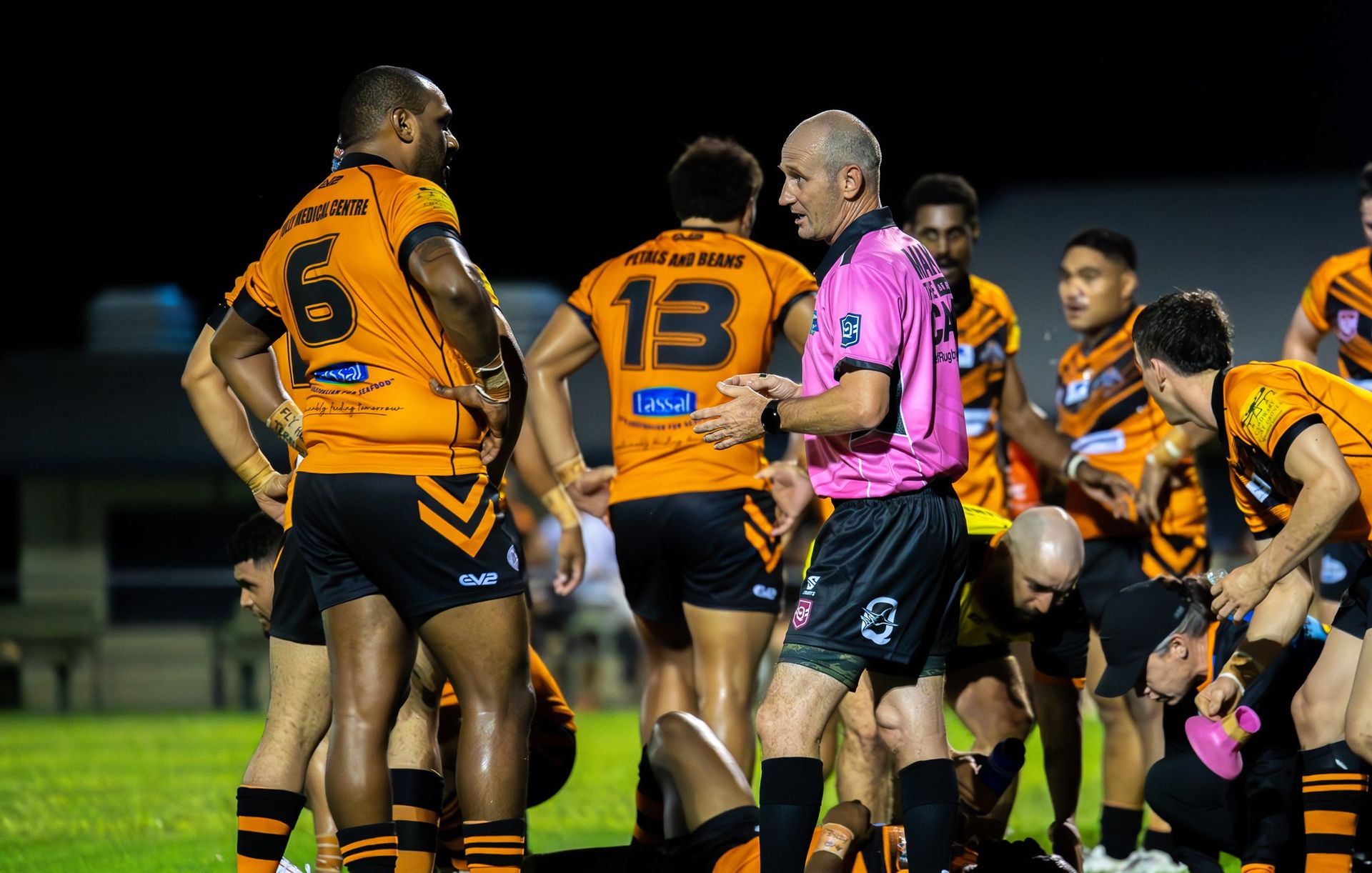 Rugby Players in Orange and Black Jerseys Huddle — Amanda Jade Photography In Gordonvale, QLD