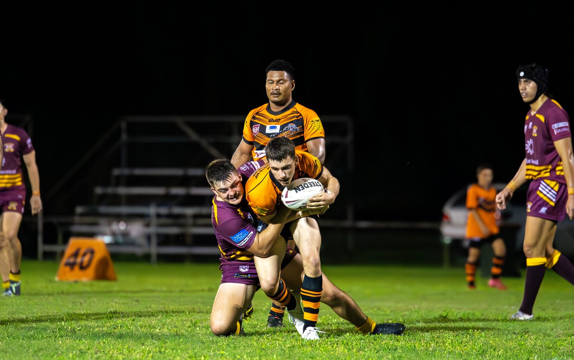 Rugby Players Tackling On A Green Field At Night — Amanda Jade Photography In Mareeba, QLD