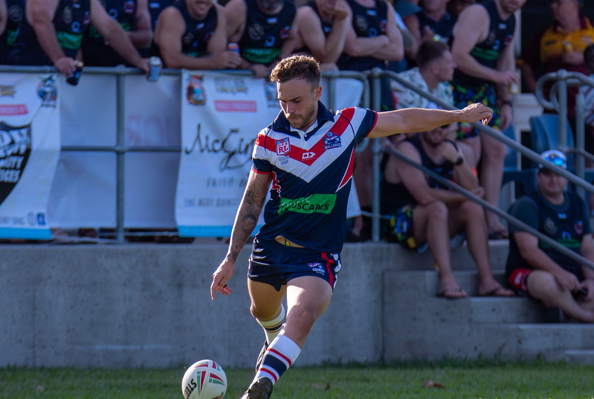 A Rugby Player In A Navy Uniform Kicking The Ball On A Green Field — Amanda Jade Photography In Atherton Tablelands, QLD