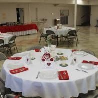 Round banquet table with white tablecloth and red napkins in a bright reception hall