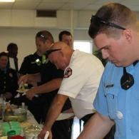 People serving food at a buffet, with one in a blue shirt in the foreground