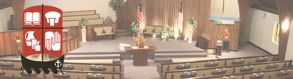 Church sanctuary with wooden pews, altar, floral arrangements, and soft ambient lighting