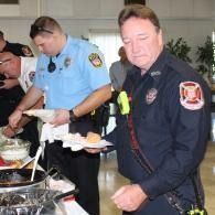Firefighters serving food at a buffet table indoors