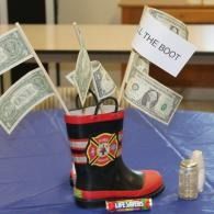 Decorated cowboy boot with cash and a “THE BOOT” sign on a table, with stacks of coins nearby