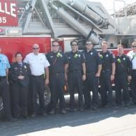 A group of firefighters and police officers standing in front of a large fire truck
