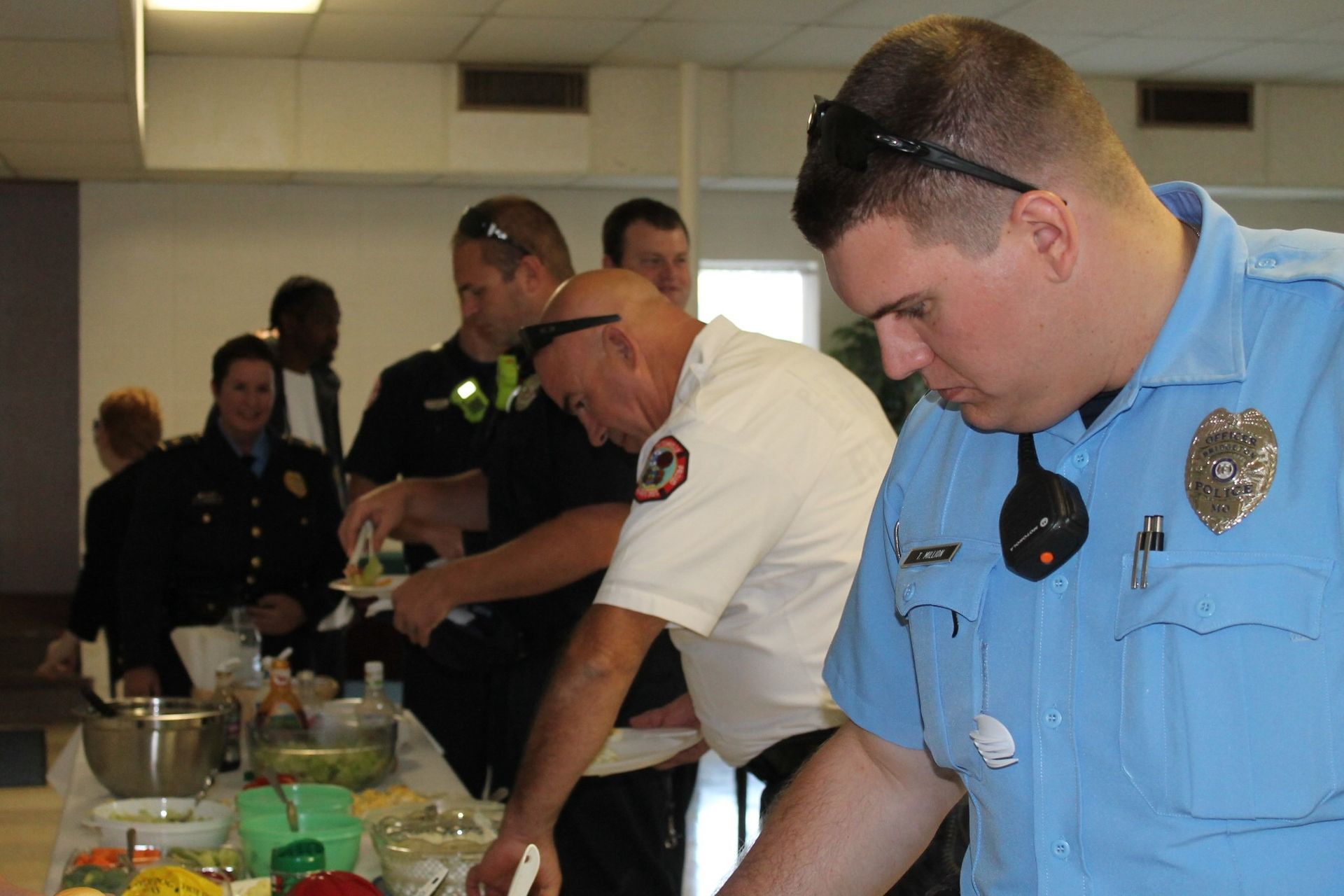 Police officers serve food at a buffet table indoors.