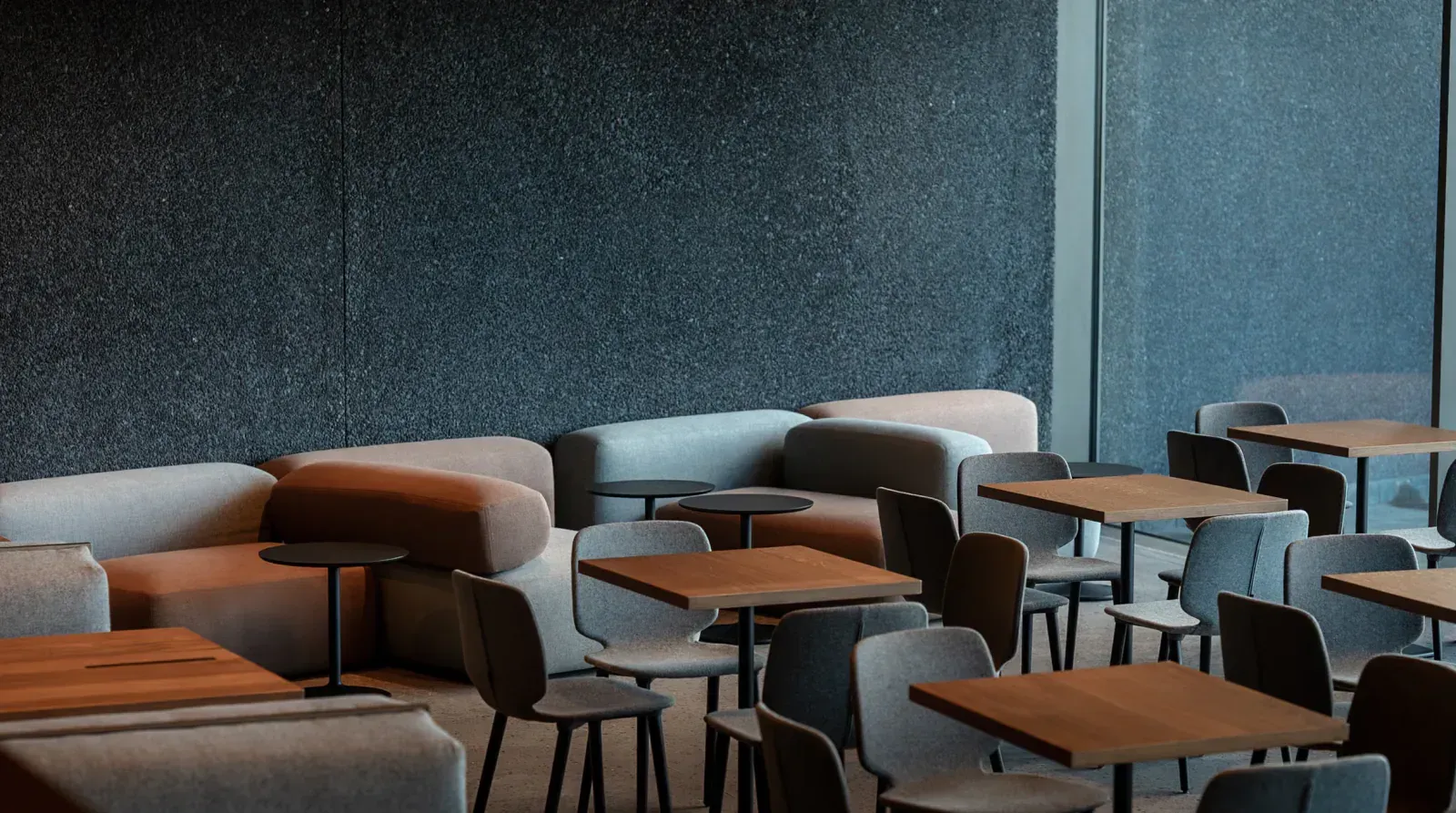 Interior of a modern cafe with patrons, a long table, and a textured wall.