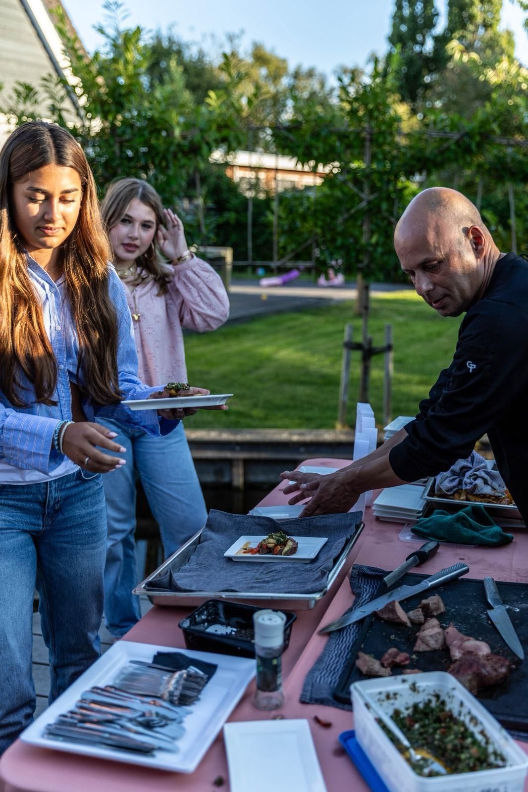 Mensen bekijken de spullen op een marktkraam in een park tijdens zonsondergang.
