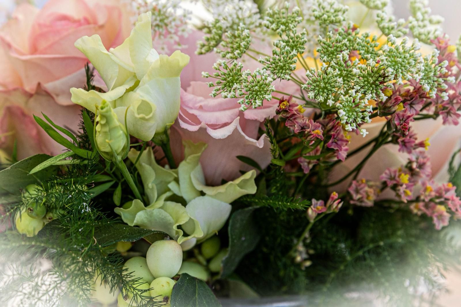 Zachtroze, witte en groene bloemen, gerangschikt in een weelderig boeket met delicate vulbloemen.