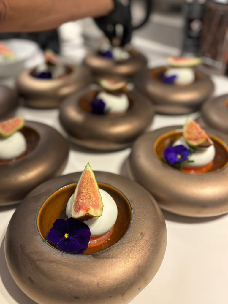 Minidesserts met chocoladeglazuur, gegarneerd met vijgen en eetbare bloemen, geserveerd op een dienblad.