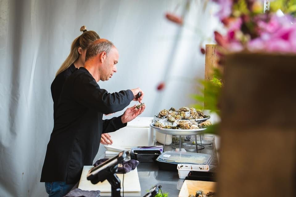 Een chef-kok schikt gerechten op een buffet in een lichte ruimte.