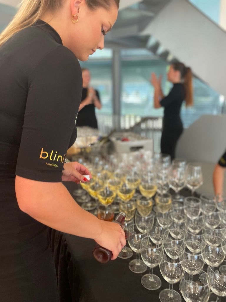 Vrouw die rijen champagneglazen op een receptietafel schikt