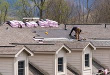 A man is working on the roof of a house.