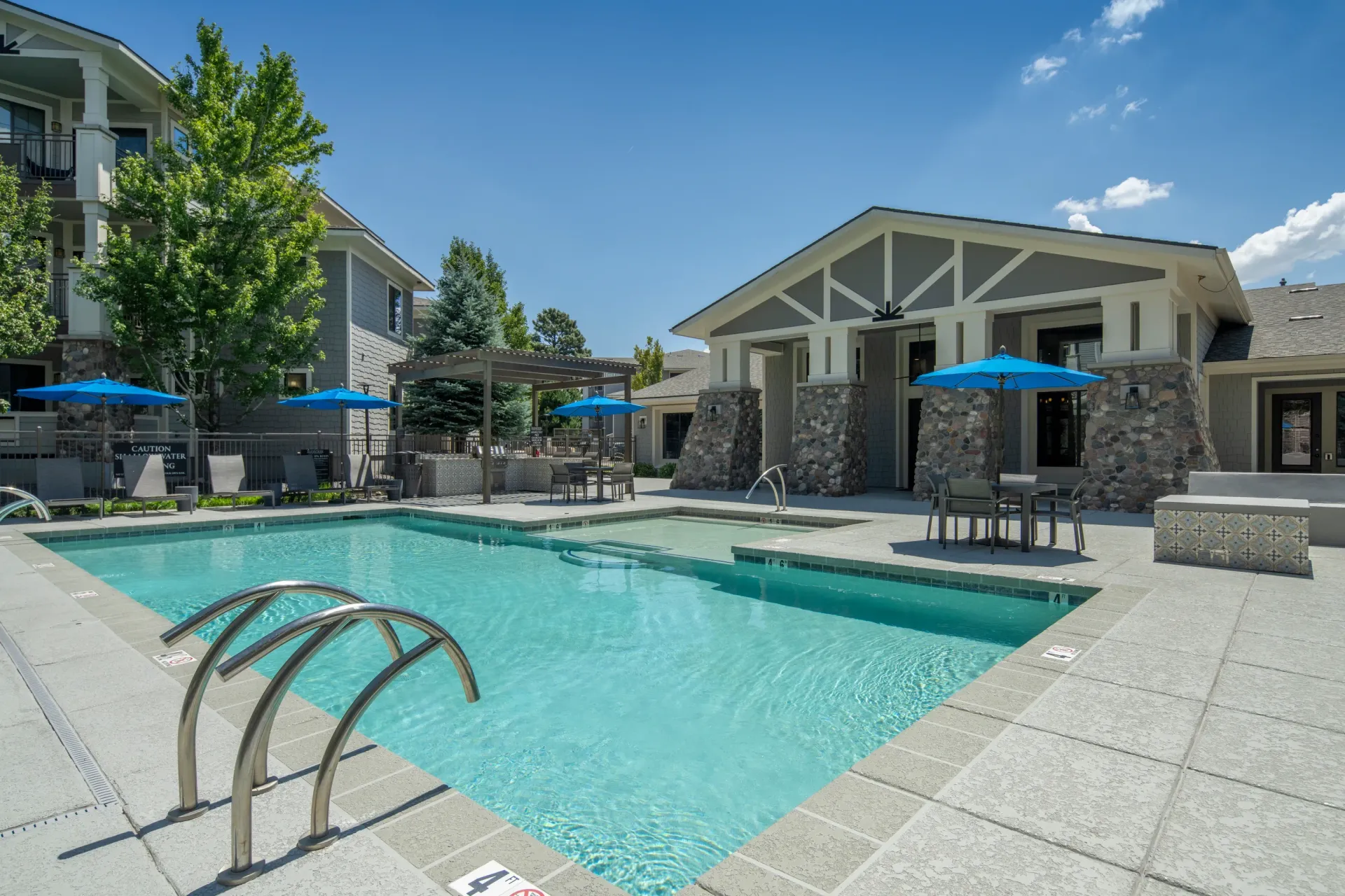 Swimming pool with lounge chairs and umbrellas at a multifamily property at Elevation in Flagstaff, AZ.