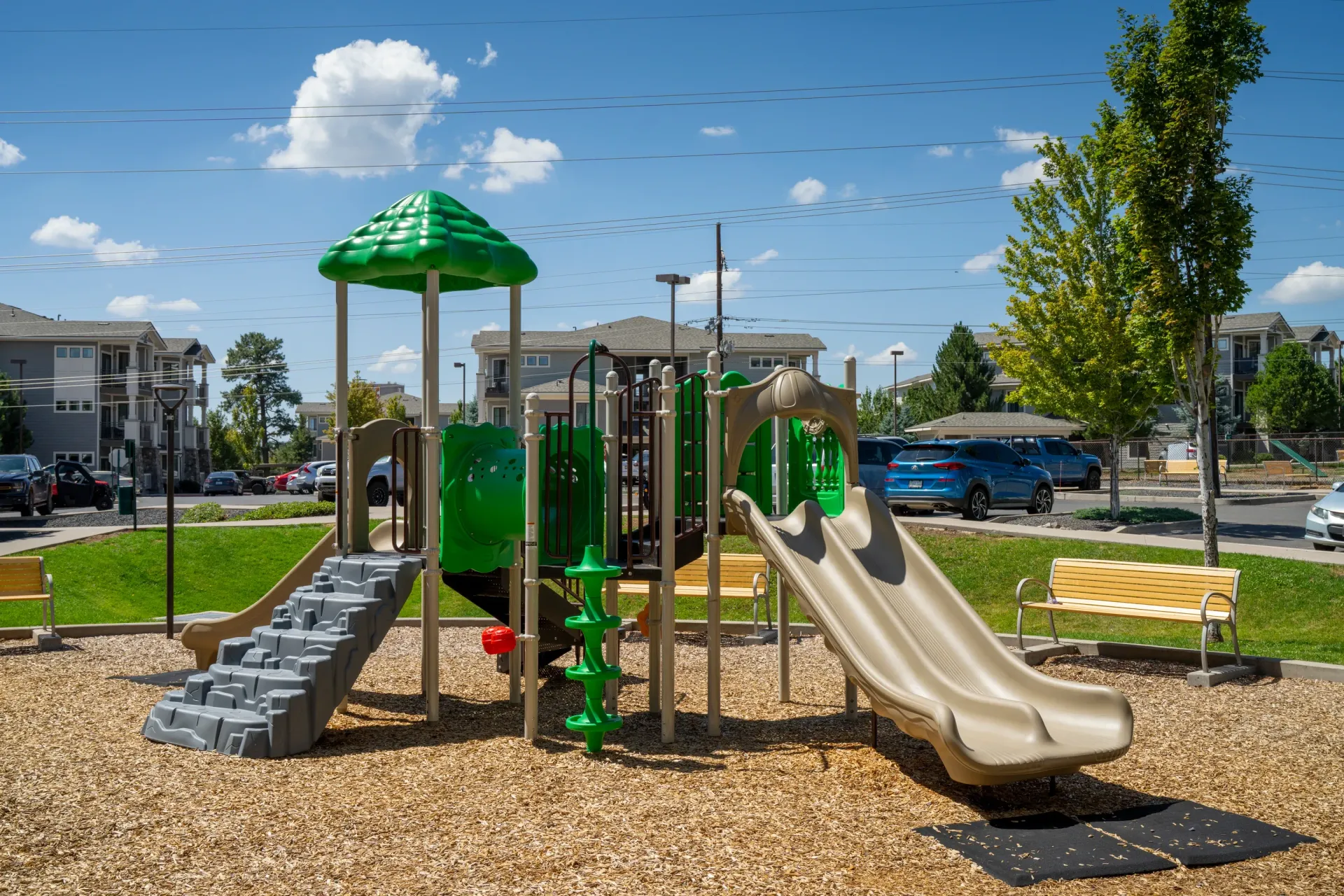 Playground equipment with slides and benches with apartment buildings in the background at Elevation in Flagstaff, AZ.